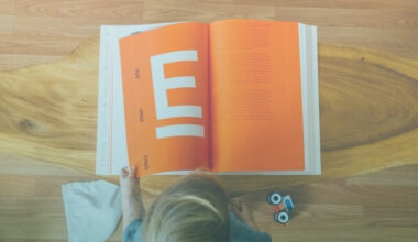 Criança lendo um grande livro com páginas laranjas.