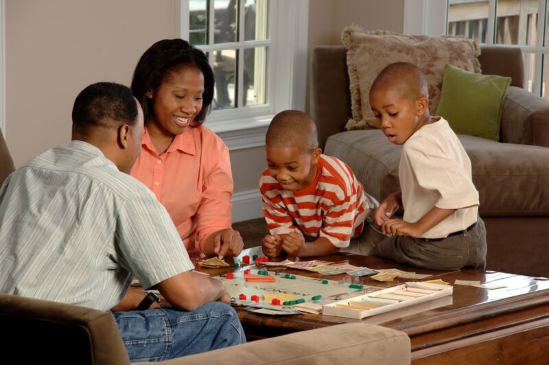 Pessoas negras brincando com jogos de tabuleiro para família.