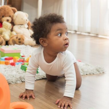 Bebê negro ao redor de brinquedos educativos