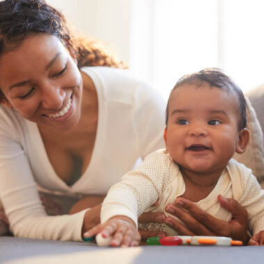 Mãe negra brincando com bebê.