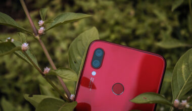 Celular Xiaomi vermelho no meio de plantas.