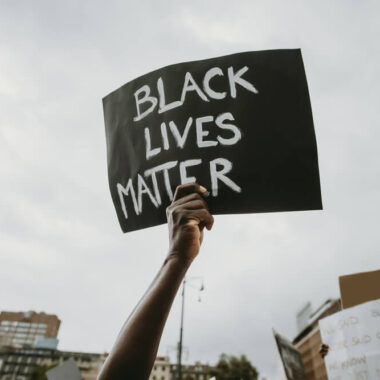 Mão segurando um cartaz escrito "black lives matter" (vidas negras importam, em inglês).