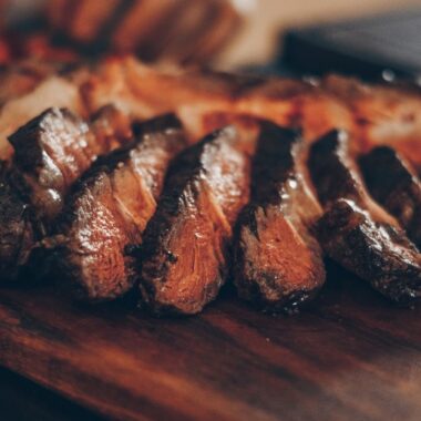 tábua de madeira para churrasco. em cima, uma carne de churrasco cortada