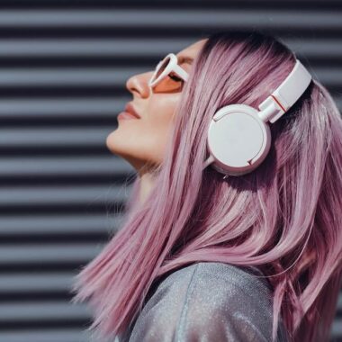 Mulher de cabelo rosa escutando música com headphones