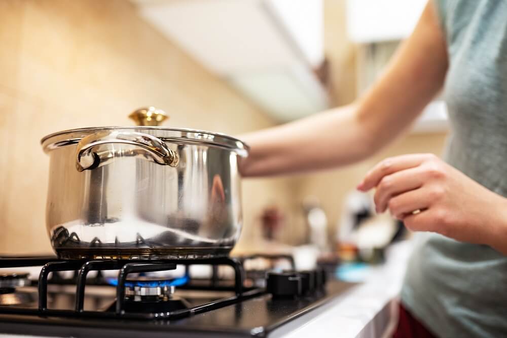 Mãos femininas mexendo em panela sob fogão