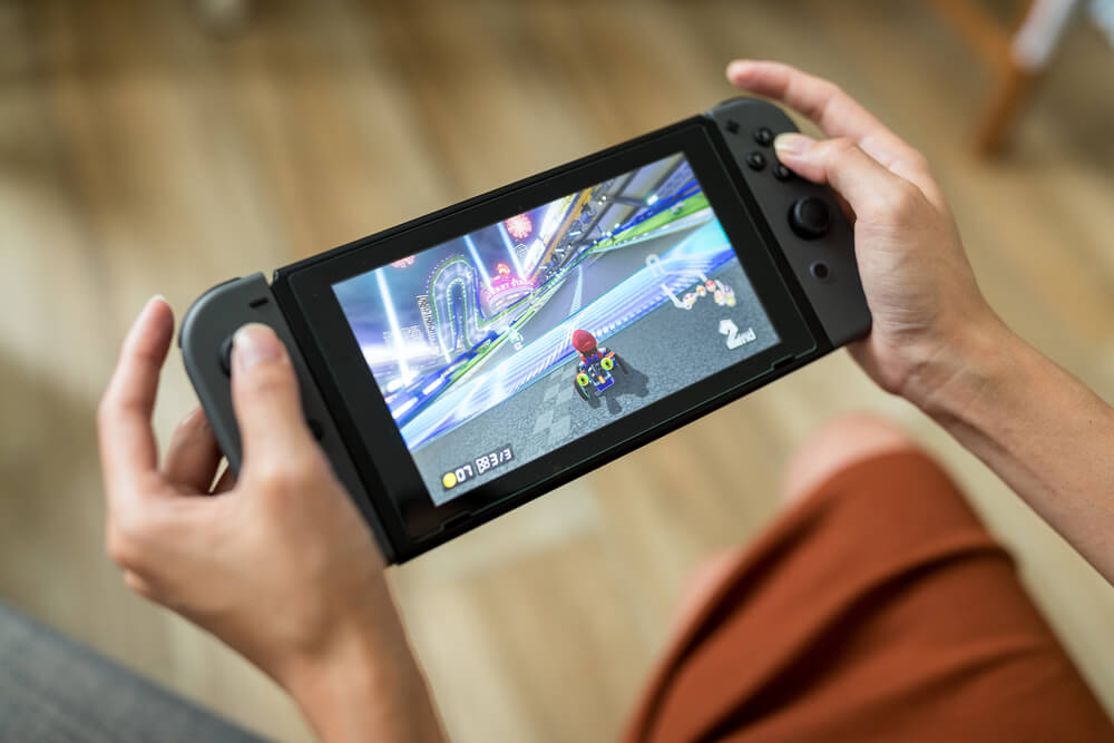 Pessoa jogando Mario Kart em um Nintendo Switch preto.
