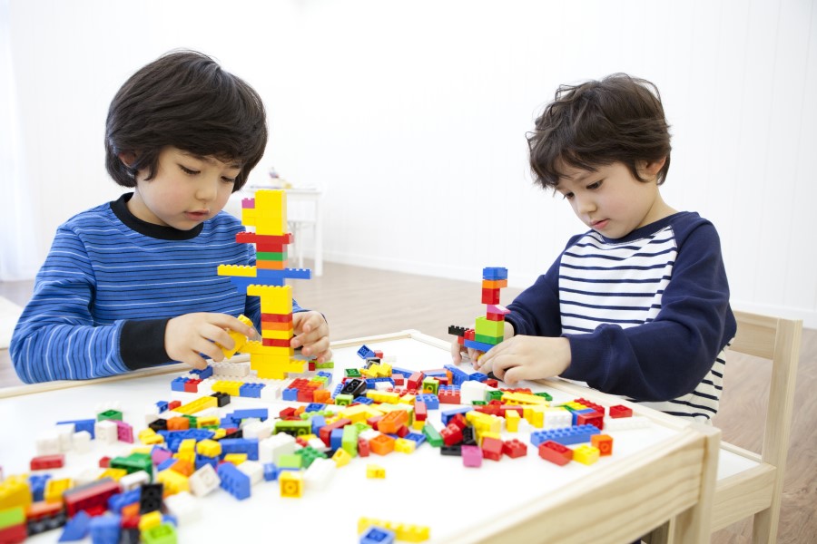 Duas crianças brincando com Lego em uma mesa.
