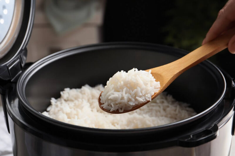 Colher de pau com arroz retirado de panela de arroz