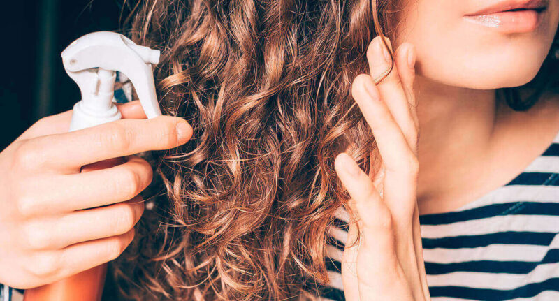 mulher de cabelo ondulado castanho aplicando um dos produtos lola cosmetics