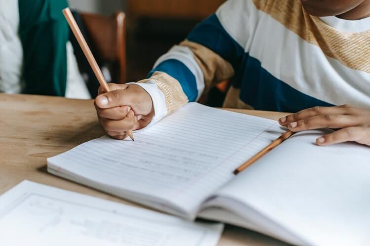 criança escrevendo em caderno